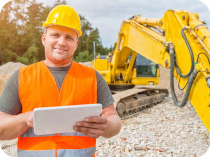 Construction worker standing on a worksite, checking business credit line requirements on a tablet.